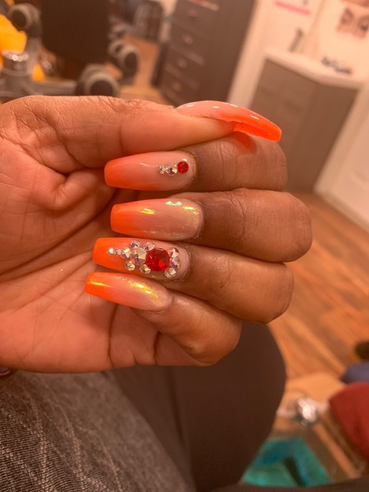 Long orange ombré nails with red rhinestone accents by J Nail Spa
